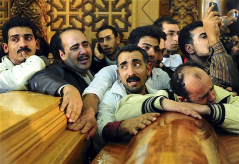 Egyptian Christians grieve in front of coffins containing the victims of a car bomb explosion which took place in front of a church in the port city of Alexandria, Egypt, Saturday Jan.1, 2011. A powerful bomb, possibly from a suicide attacker, exploded in front of a Coptic Christian church as a crowd of worshippers emerged from a New Years Mass early Saturday, killing at least 21 people and wounding nearly 80 in an attack that raised suspicions of an al-Qaida role. (AP Photo/Tarek Fawzy)